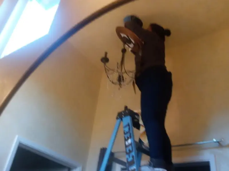 Electrician installing a chandelier in a Woodway residence